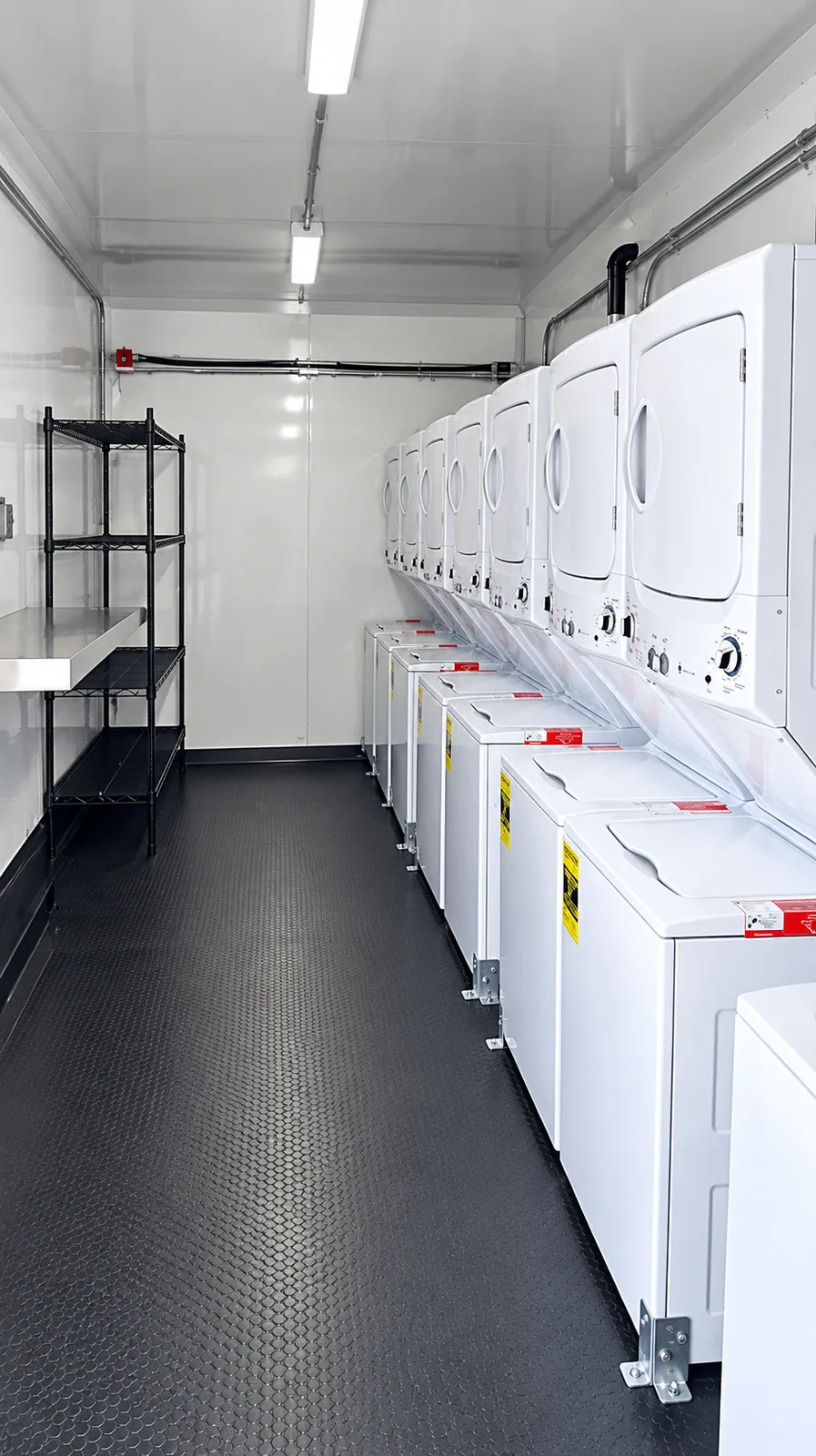 Rows of commercial washers and dryers inside a mobile laundry trailer